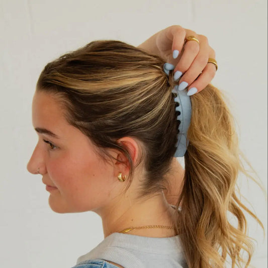 Woman with a ponytail using a hair tie against a white background
