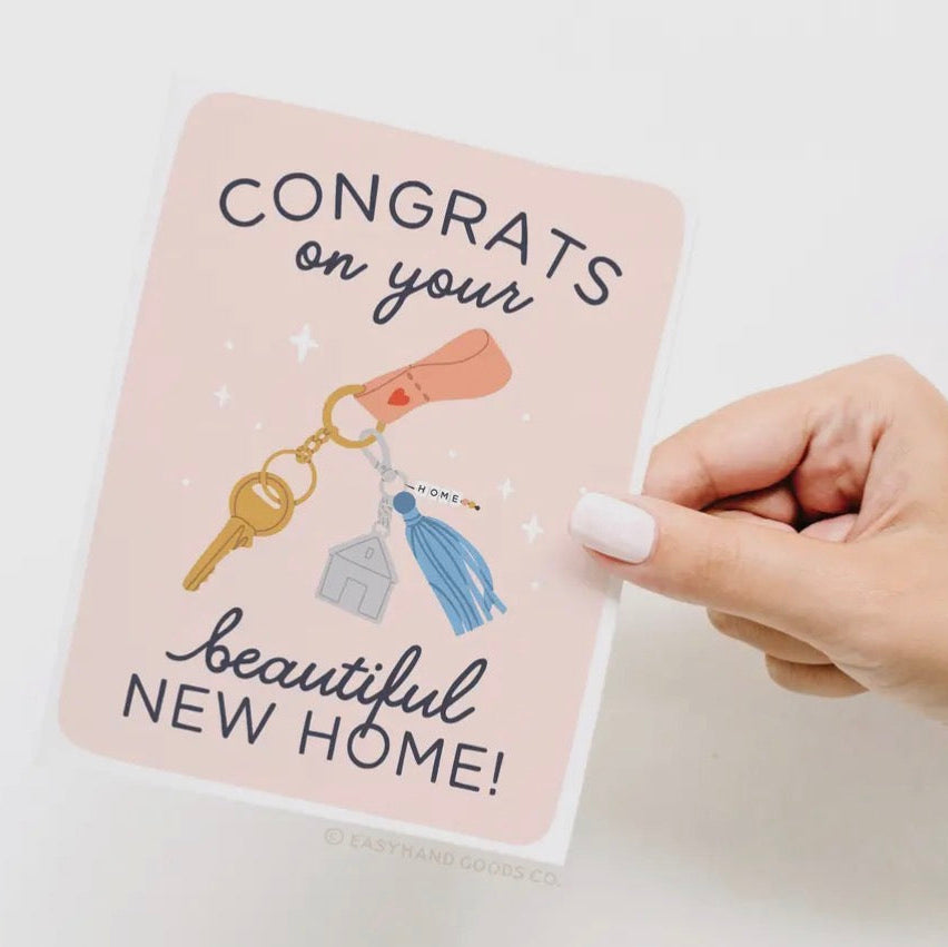 Hand holding a card with 'Congrats on your beautiful new home!' text and key illustrations.