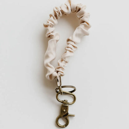 Beige scrunchie with a metal clasp on a light gray background
