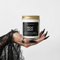 A hand with long black nails and a spider tattoo holds a candle jar labeled 'Fright Night' by Candle Bar against a plain light gray background.