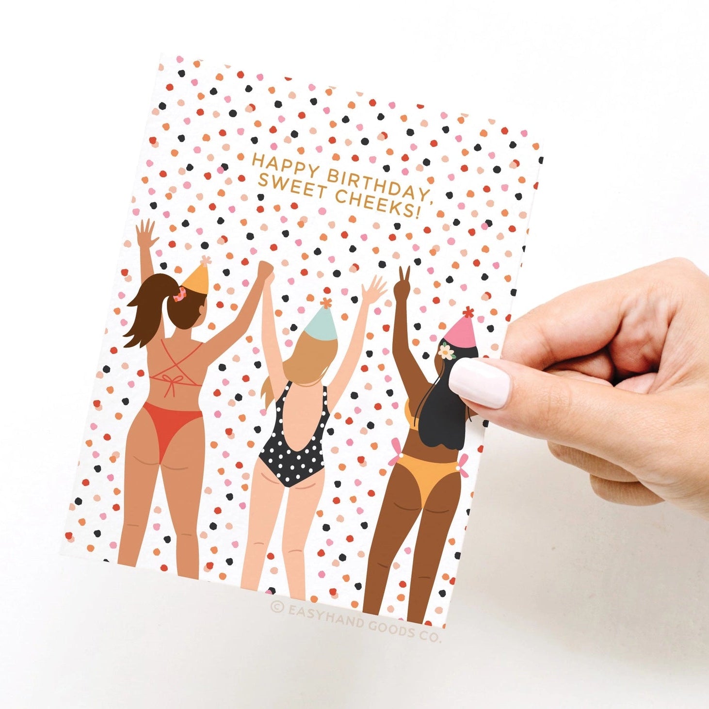 Hand holding a birthday card with illustrations of women in swimsuits and party hats.