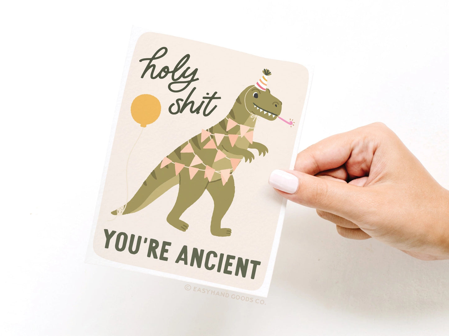 Notebook with a dinosaur illustration and humorous text held by a hand on a white background
