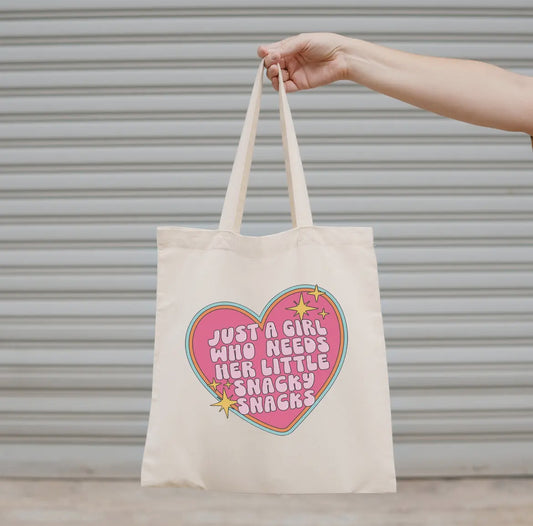 White Tote bag with a girly heart design and light pink text held by a hand against a neutral background