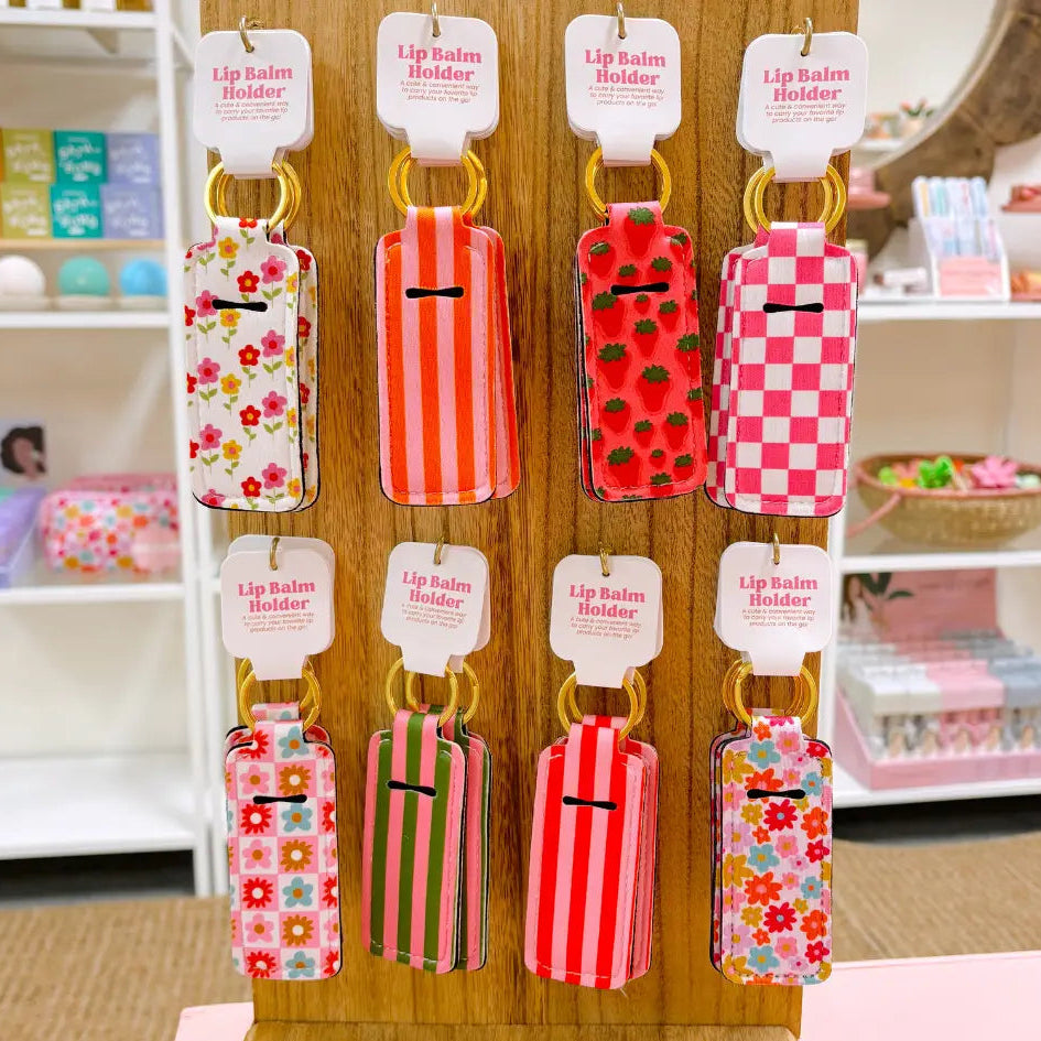 Display of colorful lip balm holders on a wooden stand with a store interior background.