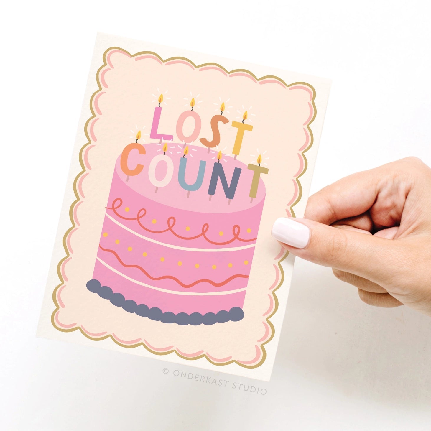Hand holding a card with a pink cake design and 'Lost Count' text on a white background