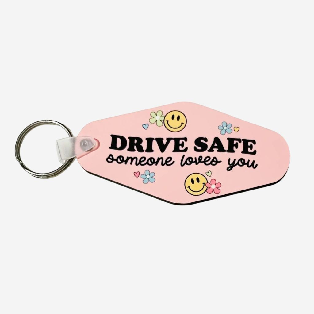 Pink keychain with 'Drive Safe, someone loves you' text and smiley faces on a white background