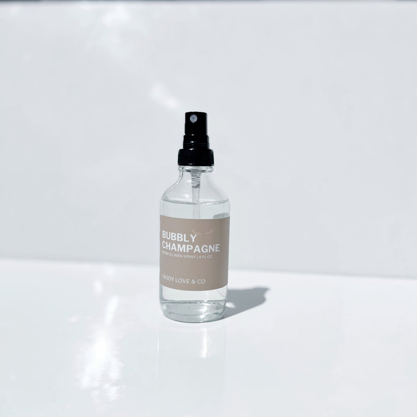 Clear spray bottle labeled 'Bubbly Champagne' on a white surface