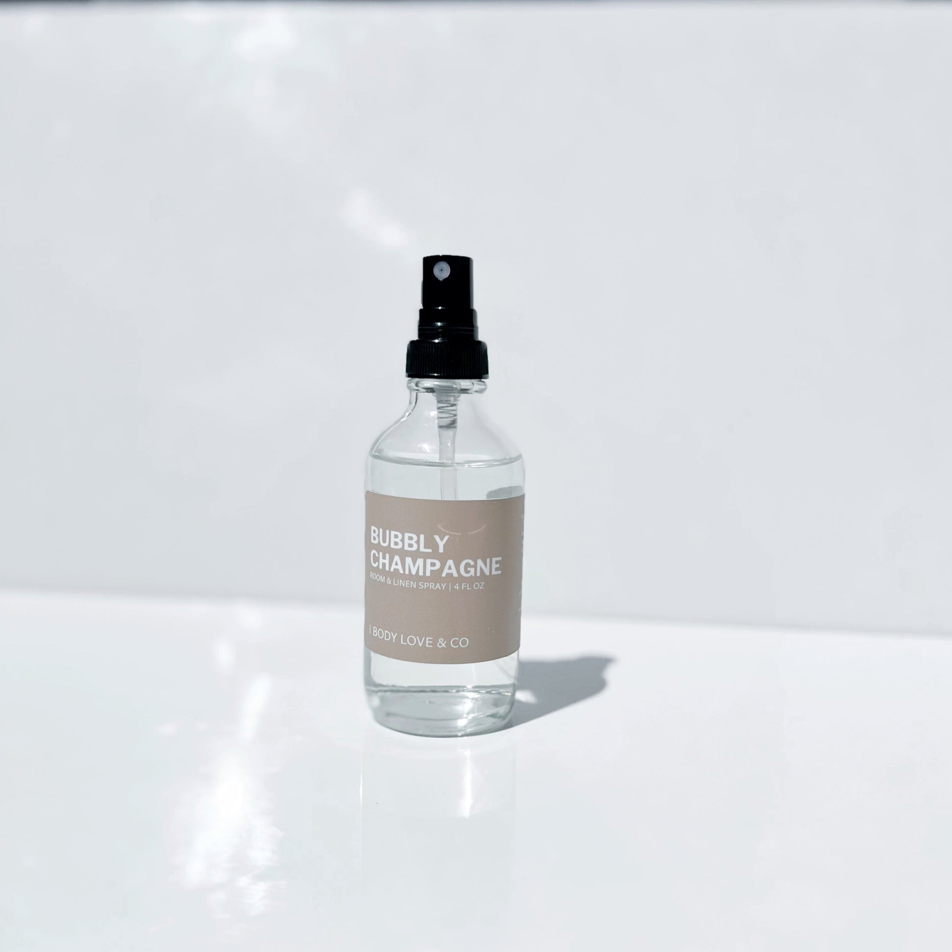 Clear spray bottle labeled 'Bubbly Champagne' on a white surface