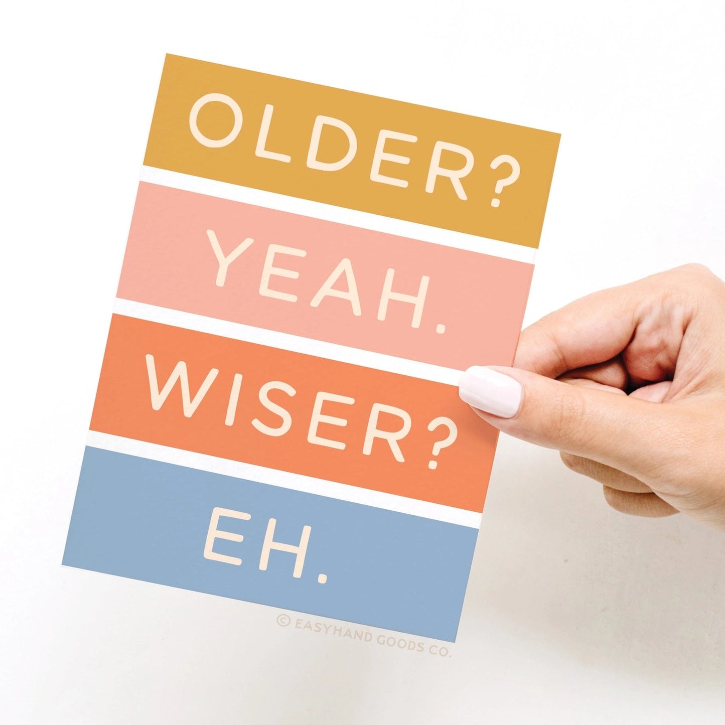 Hand holding a colorful card with text 'OLDER? YEAH. WISER? EH.'