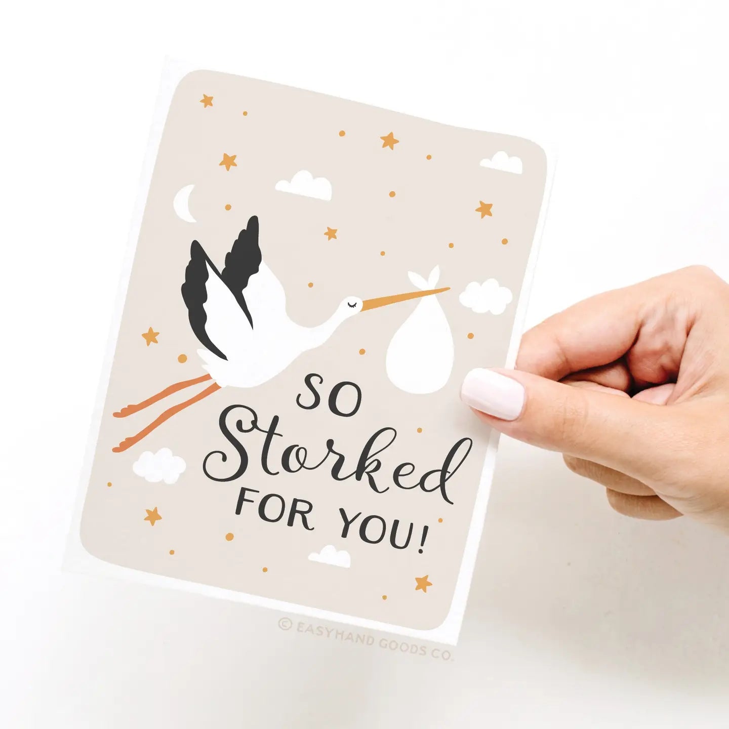 Card with stork illustration and 'So Storked For You!' text held by a hand on a white background