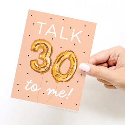 Card with 'Talk 30 to me!' text and gold balloon design, held by a hand.