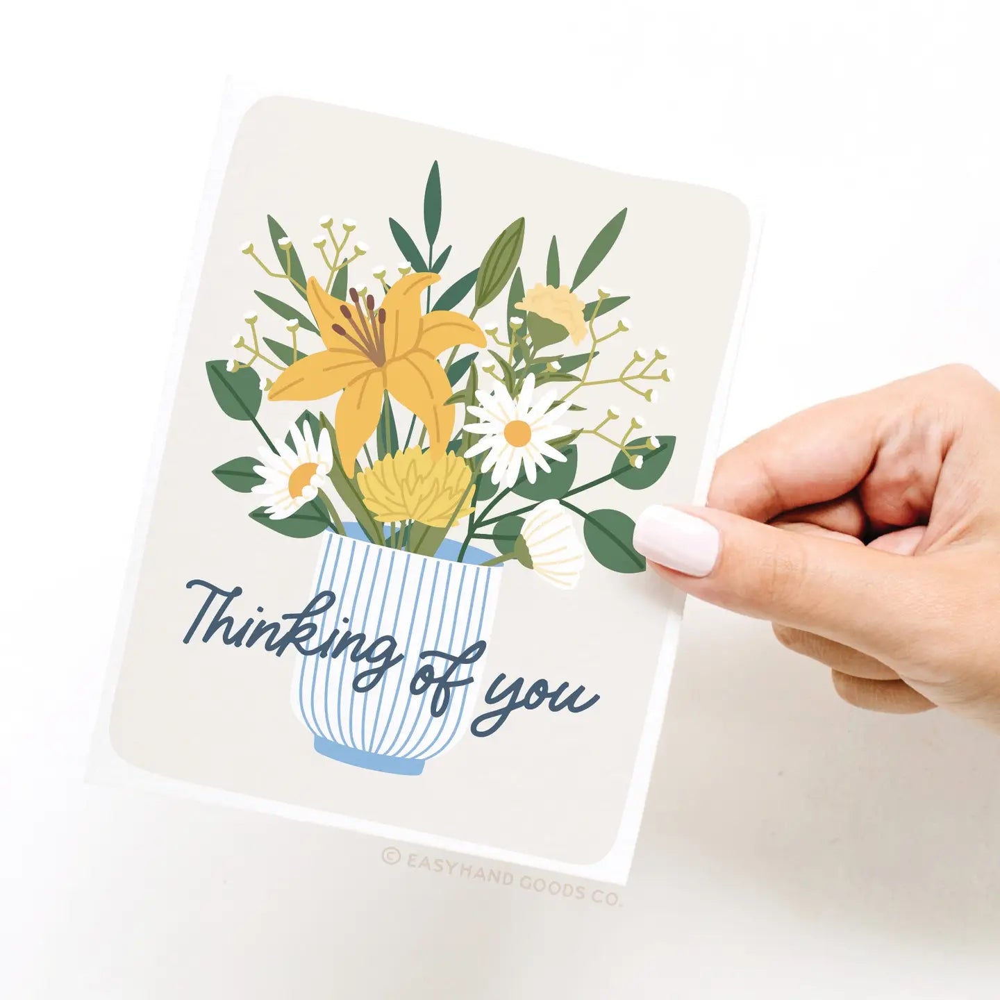 Card with floral design and 'Thinking of you' text held by a hand on a white background